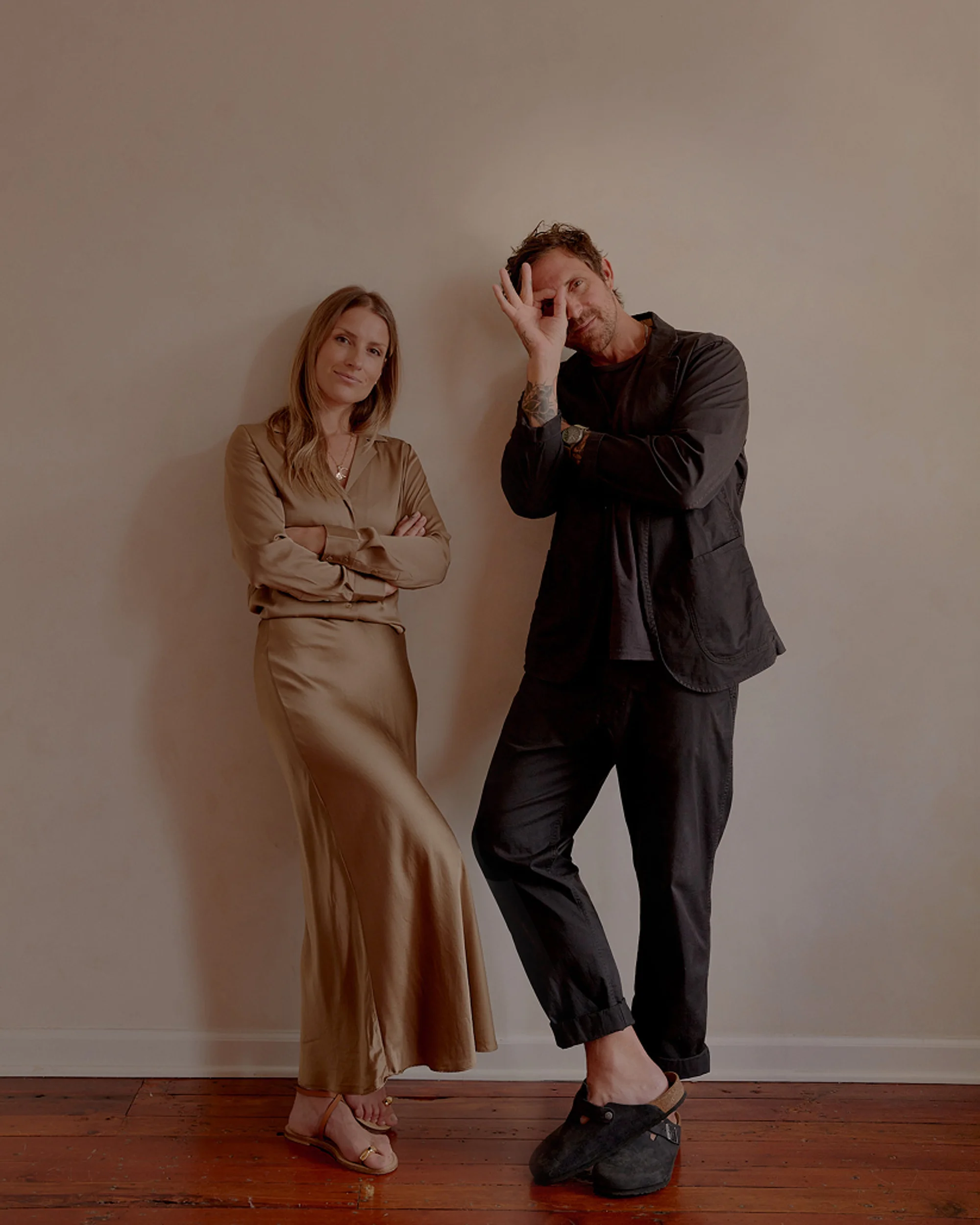 David and Johanna stand with effortless confidence and warmth, captured in a relaxed portrait that balances modern elegance with playful personality. Set against a minimalist backdrop, their understated styling and natural connection create a timeless, intimate feel.